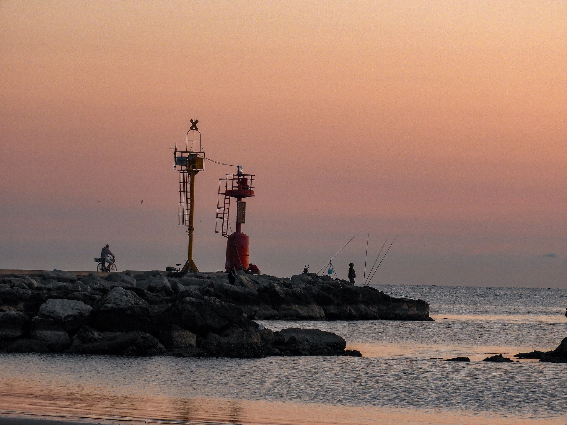 The Levante pier in Cesenatico at dawn, with anglers and the red beacon