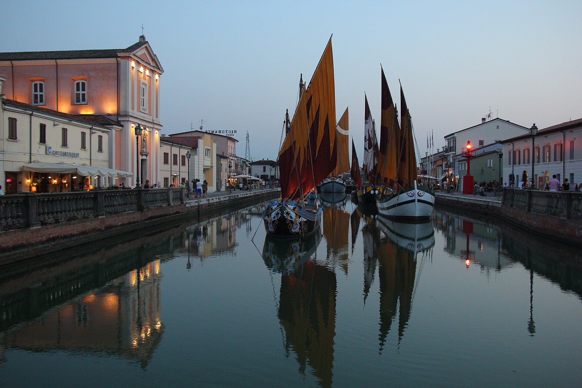 The canal harbour of Cesenatico at dusk, with the historic boats lit up
